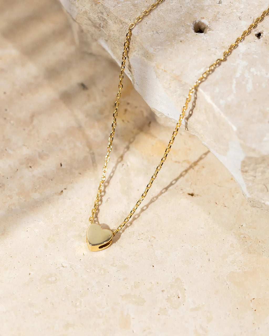 A gold-tone heart pendant necklace displayed on a stone surface (PAVOI reference image; supplier appearance awaits verification)