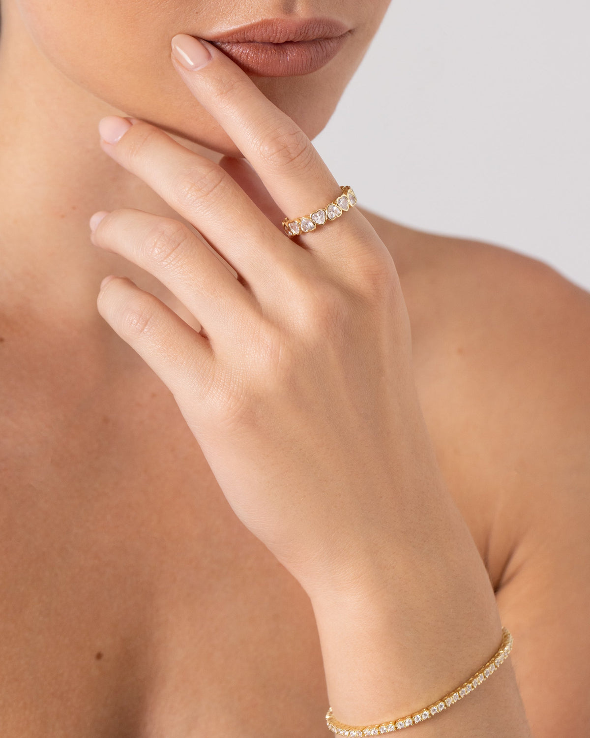 A gold-tone heart-stone eternity ring worn on a finger (PAVOI reference image; supplier appearance awaits verification)