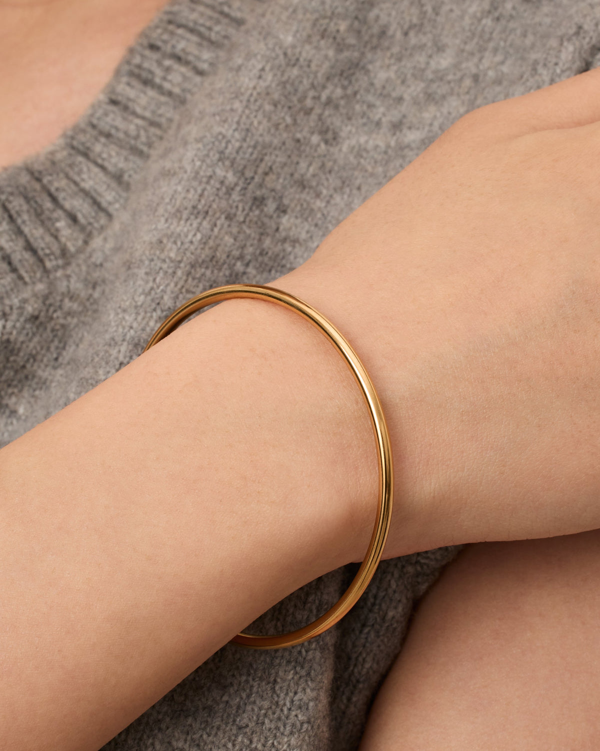 A slim gold-tone bangle bracelet worn on a model's wrist (PAVOI reference image; supplier appearance awaits verification)