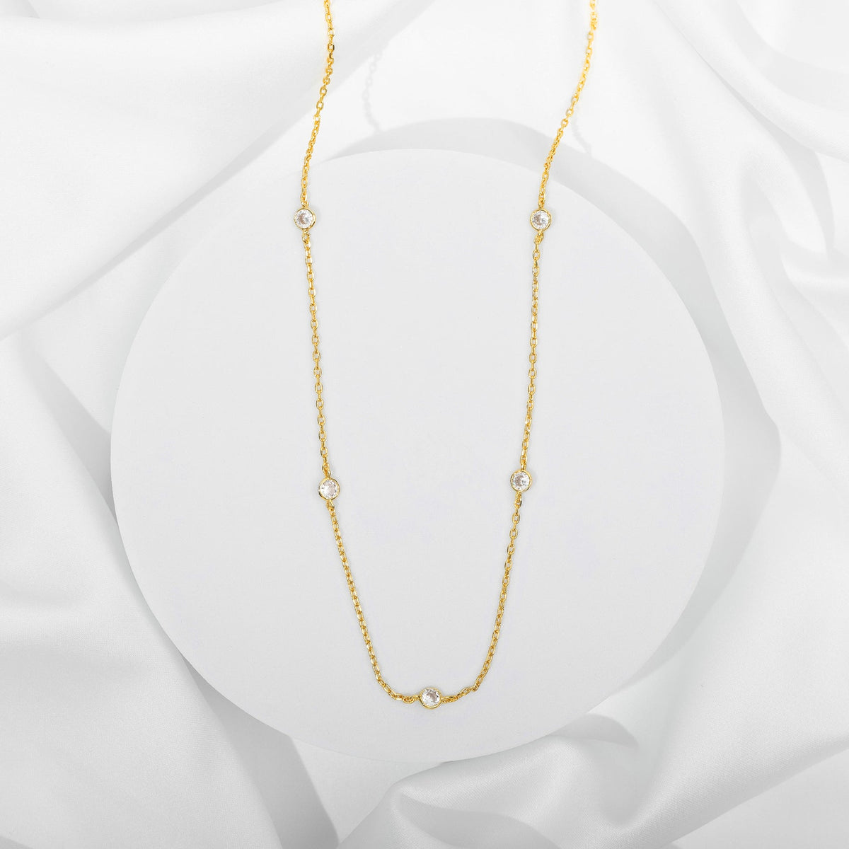 A gold-tone station necklace with round clear stones displayed on a white surface (PAVOI reference image; supplier appearance awaits verification)
