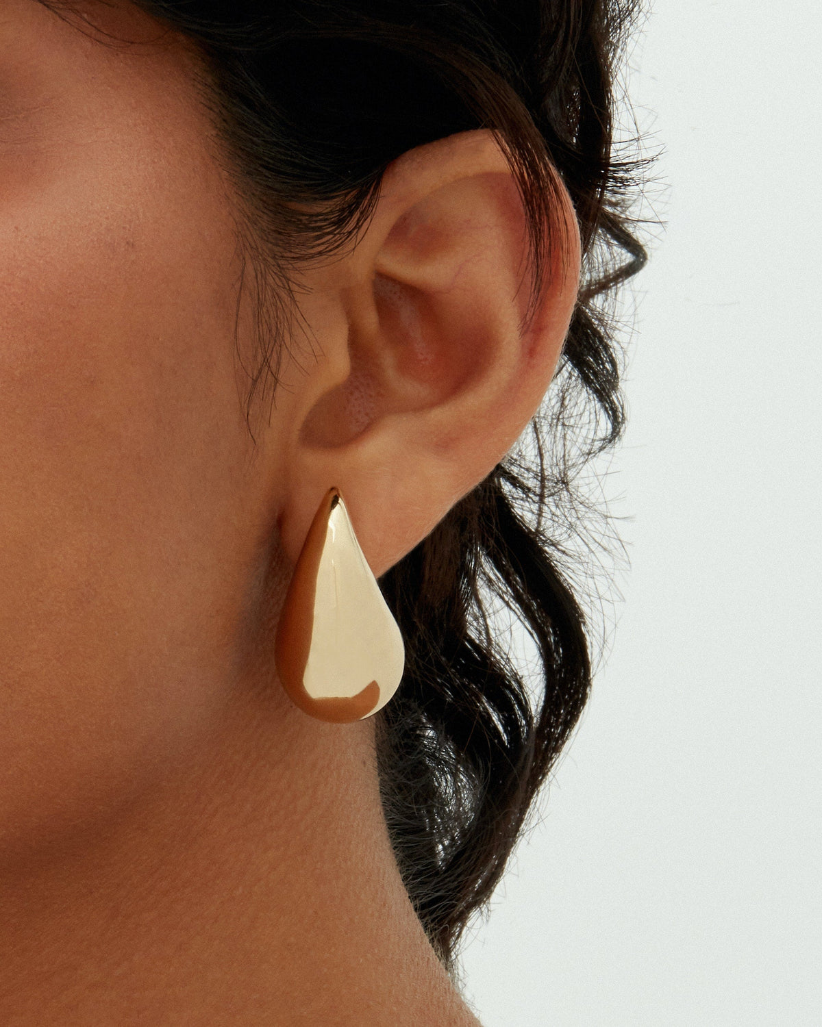 A gold-tone teardrop earring worn on a model's ear (PAVOI reference image; color illustration; supplier dimensions unverified)
