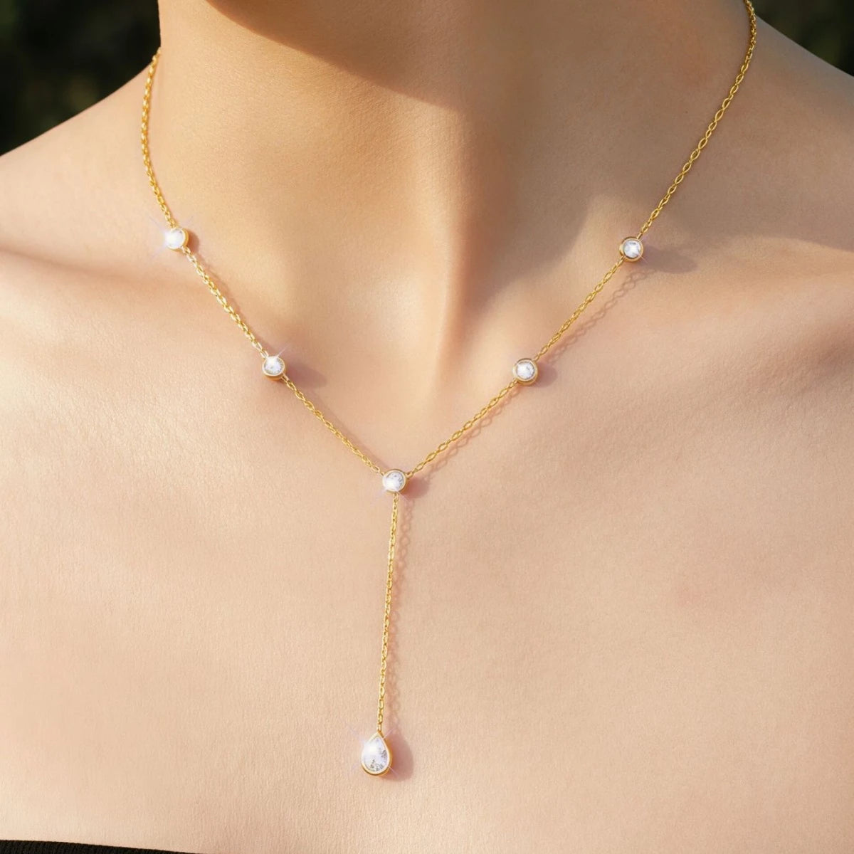 Gold-tone Y-necklace with clear stones and a teardrop pendant worn on a model