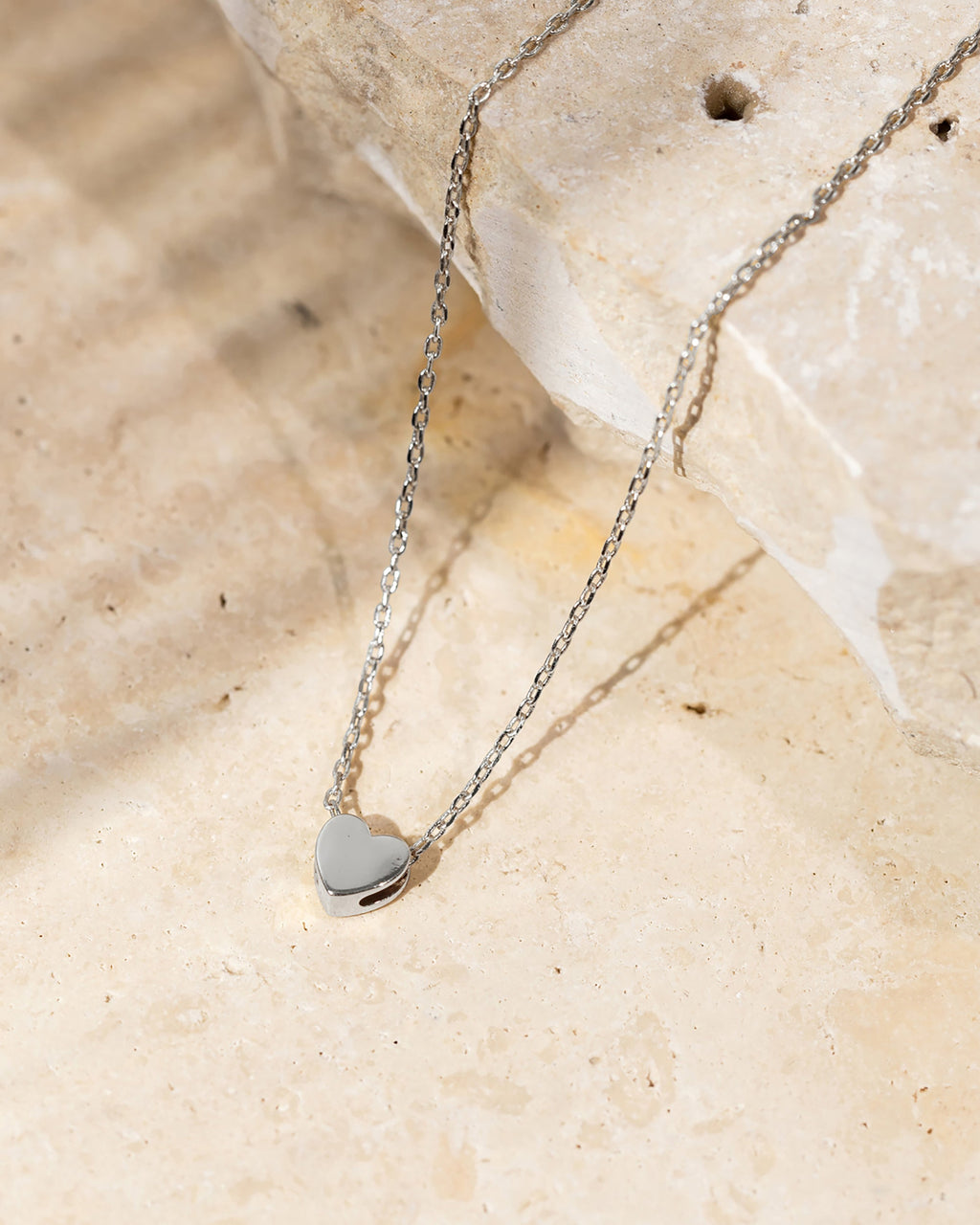 A silver-tone heart pendant necklace displayed on a stone surface (PAVOI reference image; supplier appearance awaits verification)