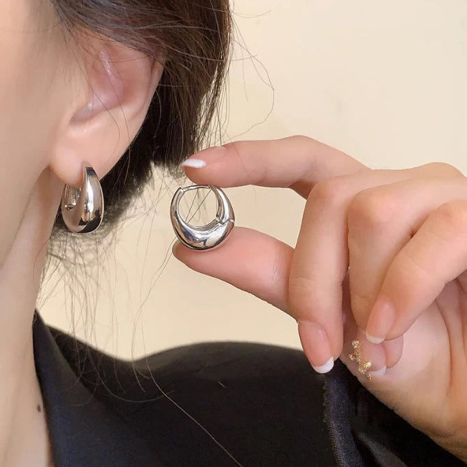 Supplier silver-tone smooth oval hoop earrings shown worn and held