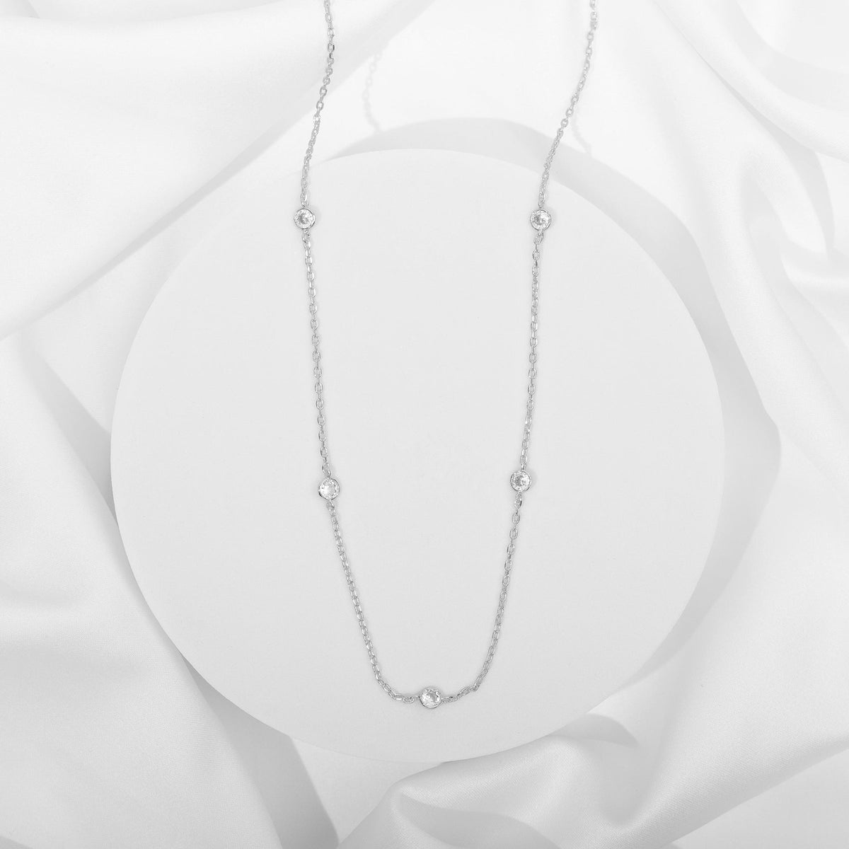 A silver-tone station necklace with round clear stones displayed on a white surface (PAVOI reference image; supplier appearance awaits verification)
